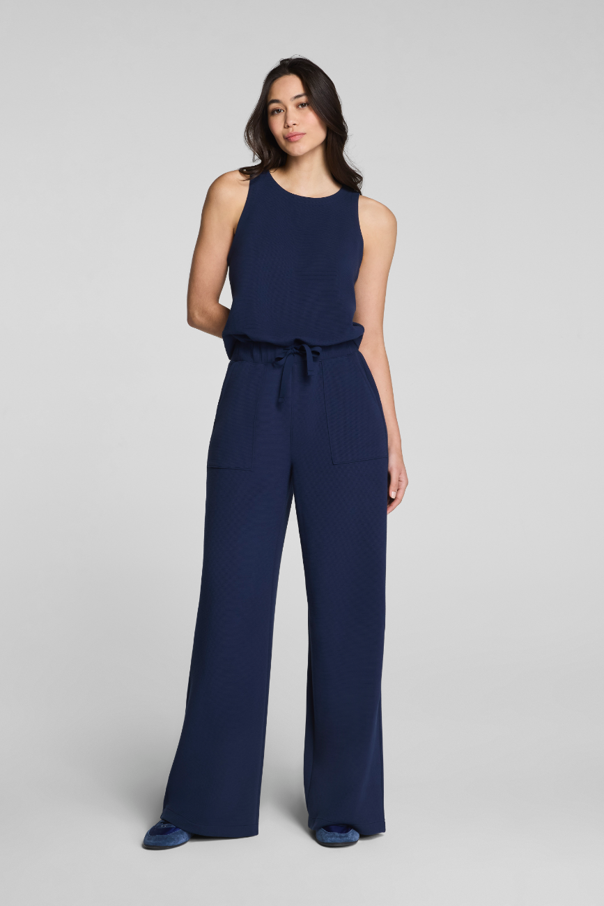 Woman wearing a navy blue jumpsuit on a light gray background