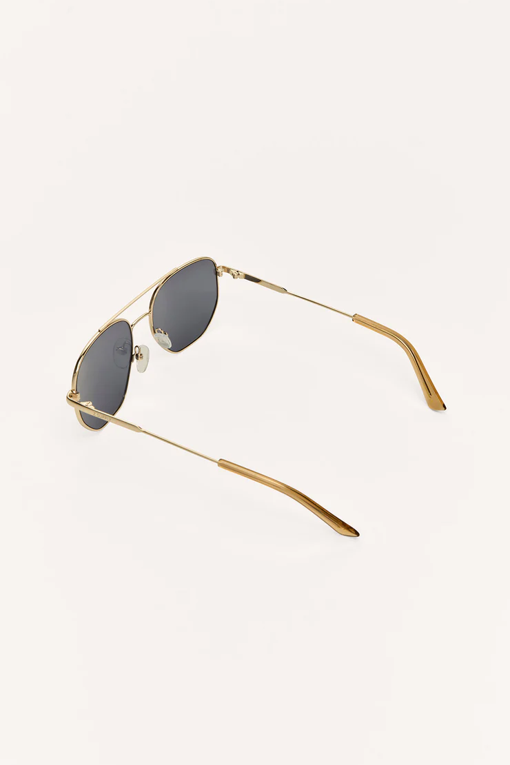 Gold-framed sunglasses with dark lenses on a white background