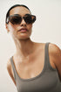 Woman wearing sunglasses and a tank top against a plain background