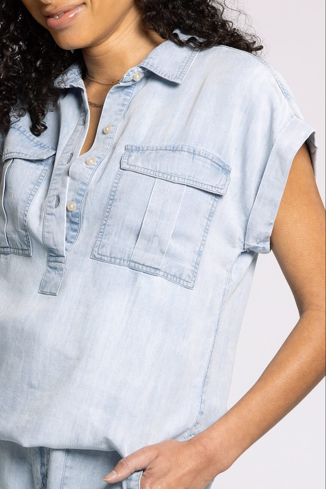 Woman wearing a light blue denim shirt against a plain background