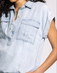 Woman wearing a light blue denim shirt against a plain background