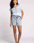 Woman wearing a light blue denim romper on a white background