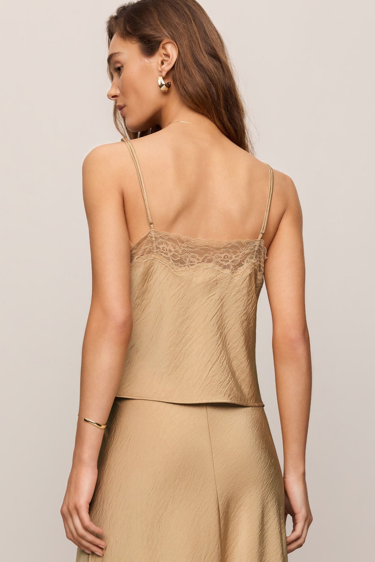Woman wearing a beige lace-trimmed top and skirt set on a neutral background