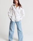 Woman wearing a white shirt and light blue jeans on a white background