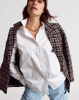 Woman wearing a white shirt, tweed jacket, and cap on a plain background