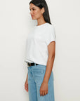 Woman wearing a white t-shirt and light blue jeans against a plain background