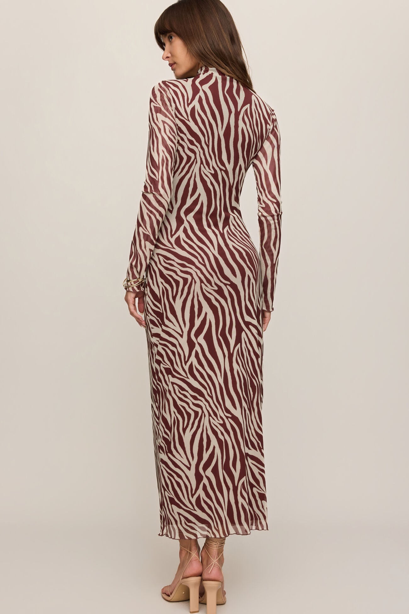 Woman wearing a zebra print dress on a plain background