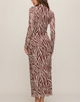 Woman wearing a zebra print dress on a plain background